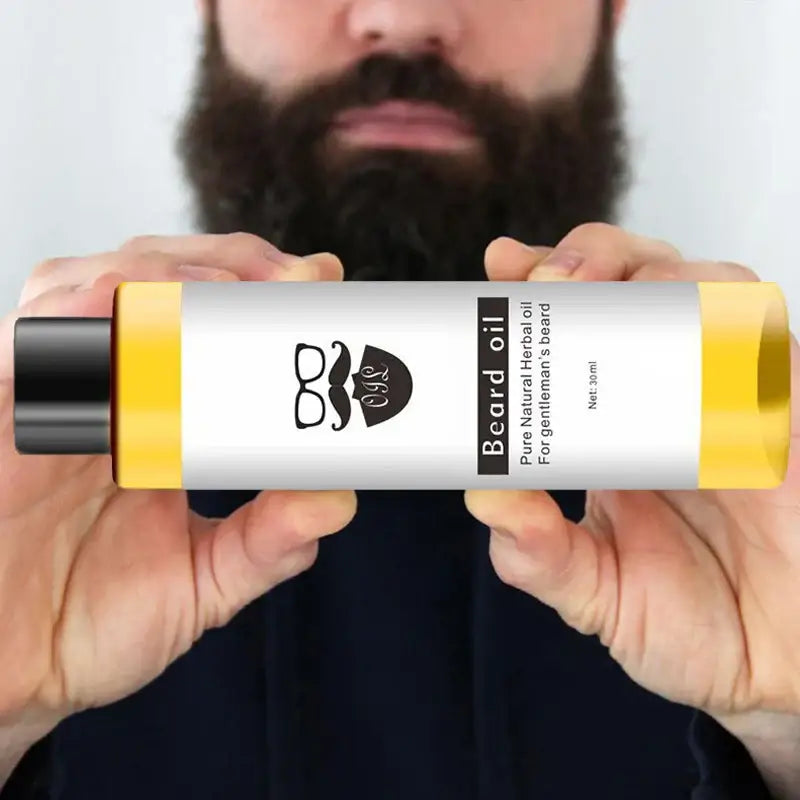 Bottle of beard oil held by hands with a beard visible behind it.