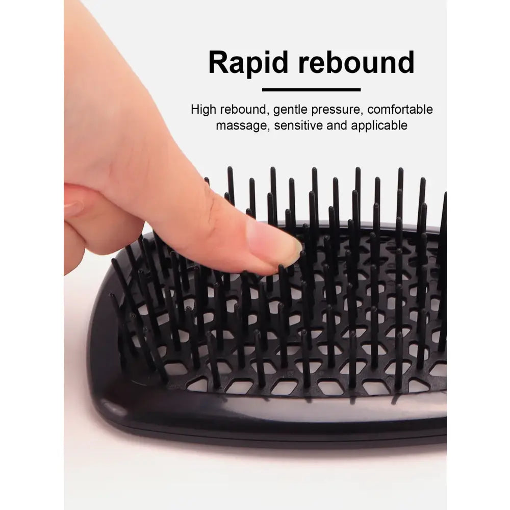 Hairbrush with dense, flexible bristles being pressed by a finger.