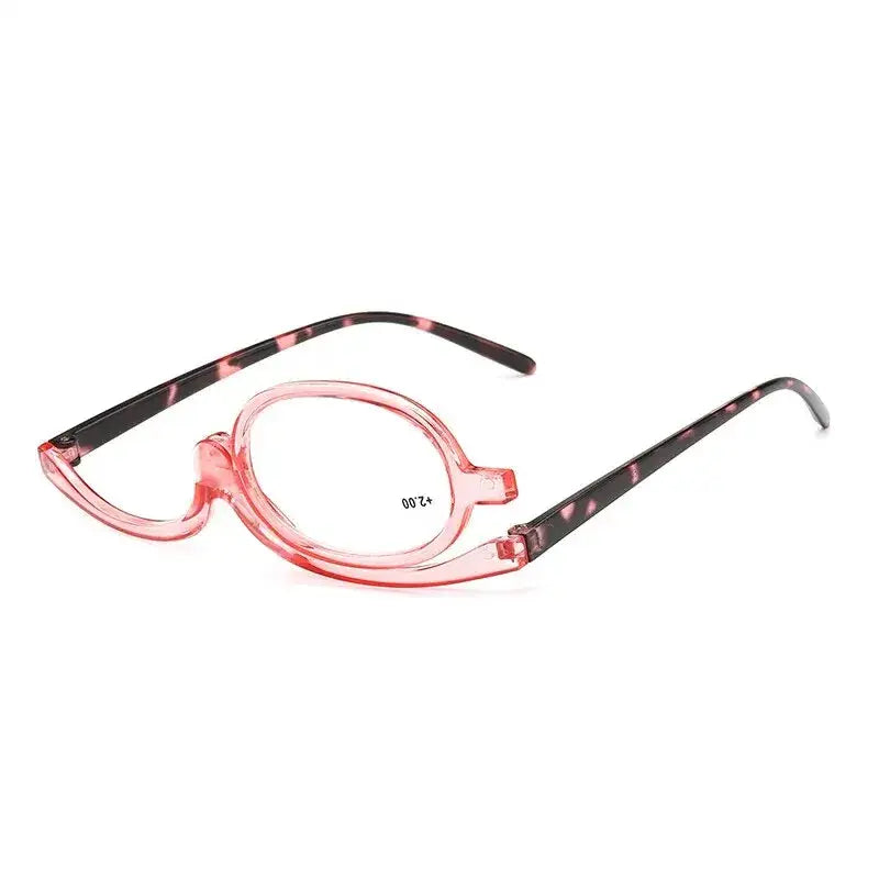 Pink-framed makeup application glasses with a flip-down magnifying lens.