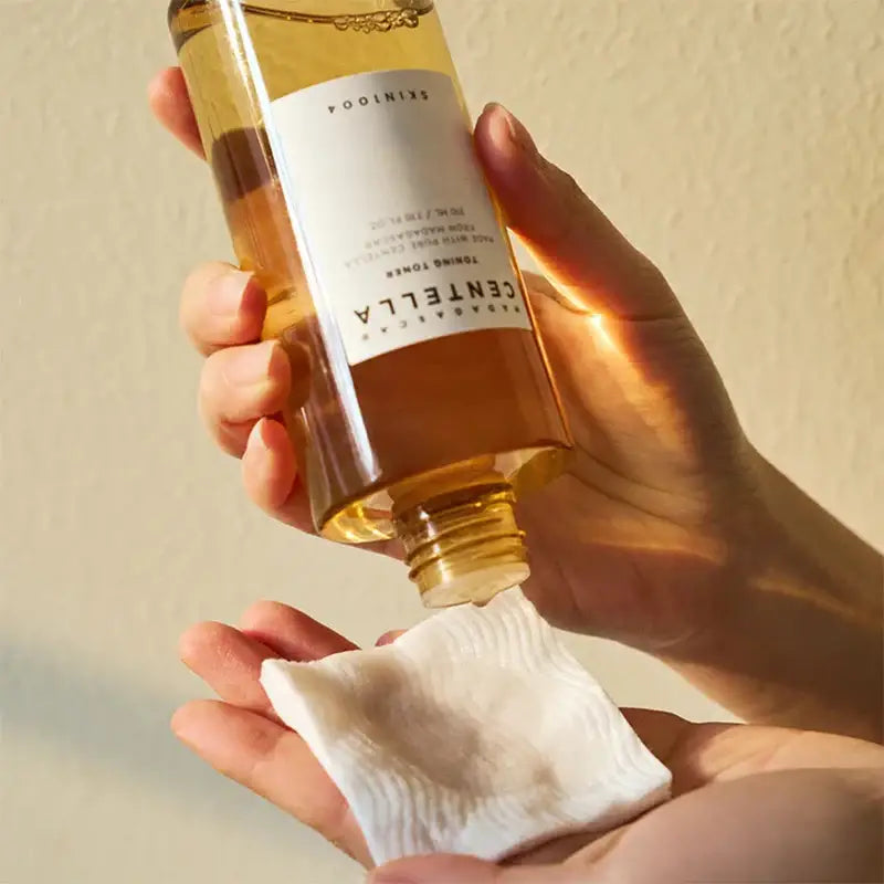 Bottle of Estrella wine being poured onto a white cloth or pad held in a hand.