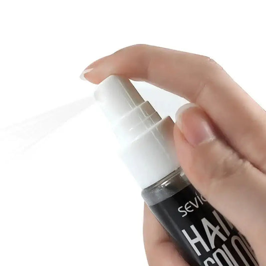 Hair spray bottle being held and sprayed by a hand.