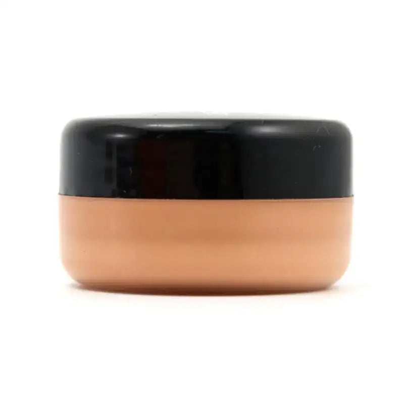 Cosmetic jar with a black lid and peach-colored base.