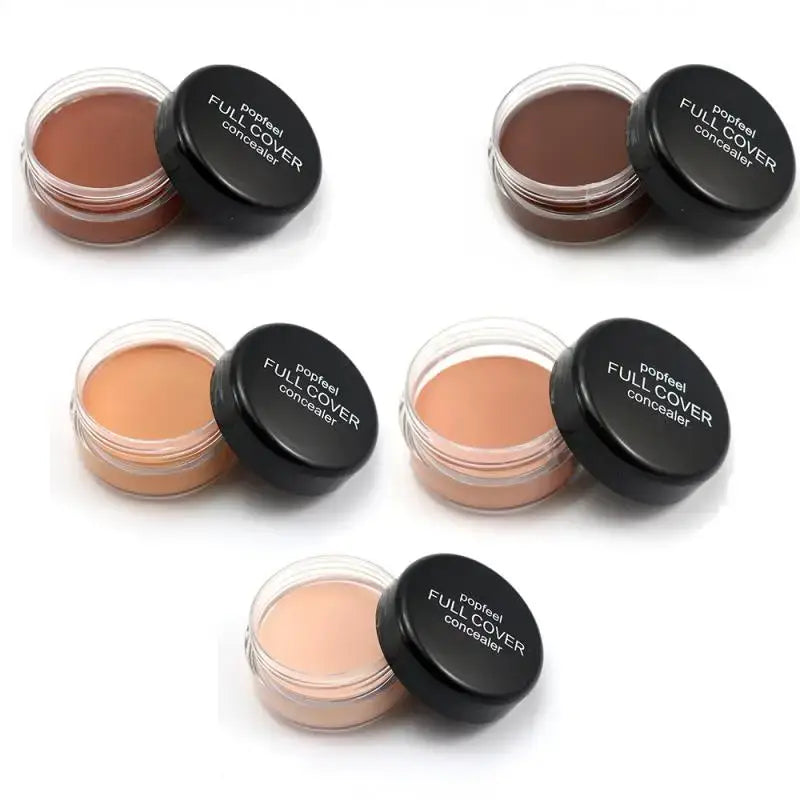 Cosmetic concealer pots in various skin tone shades with black lids.