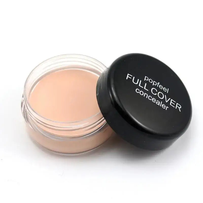 Jar of cream-colored concealer makeup with a black lid labeled ’Full Cover concealer’.