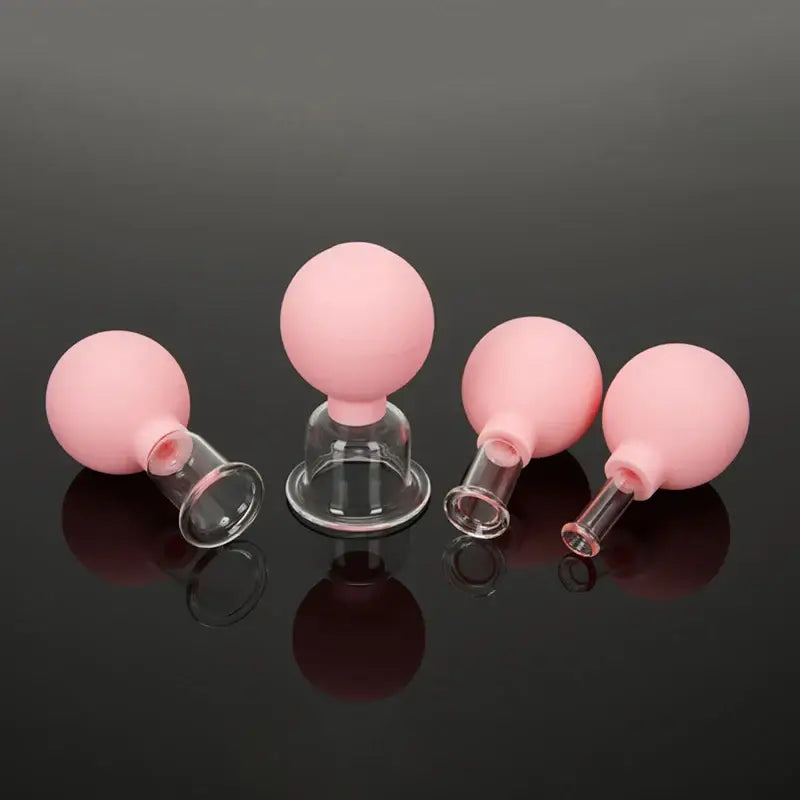 Set of pink silicone cupping therapy cups with glass bases.