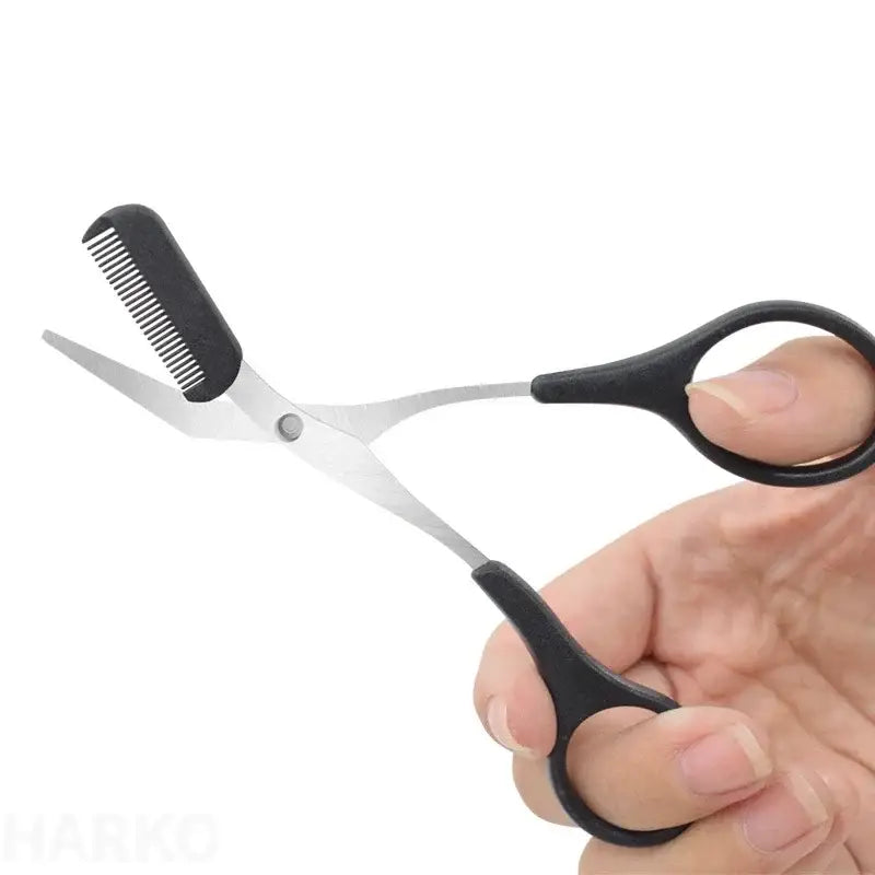 Scissors with a comb attachment held in a hand.