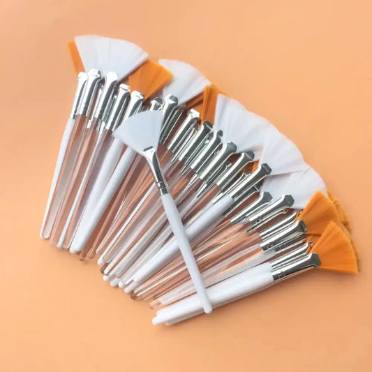 Set of makeup brushes with white handles and orange tips fanned out.