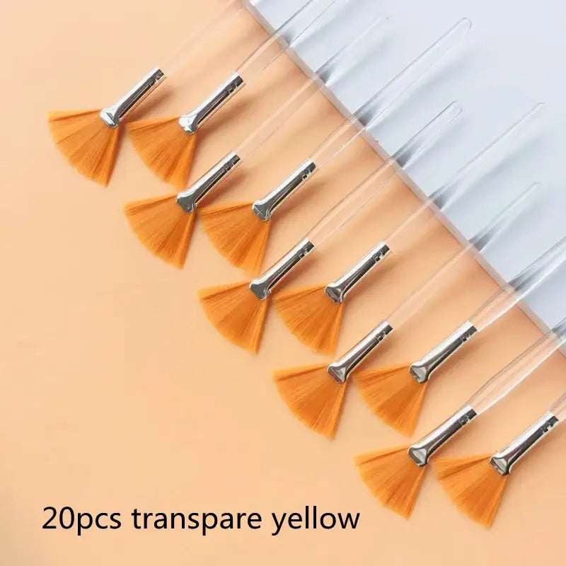 Fan-shaped orange brushes with metal handles arranged in a row.