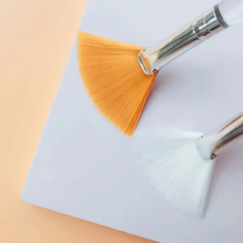 Fan-shaped paintbrush with orange bristles and a metal ferrule.