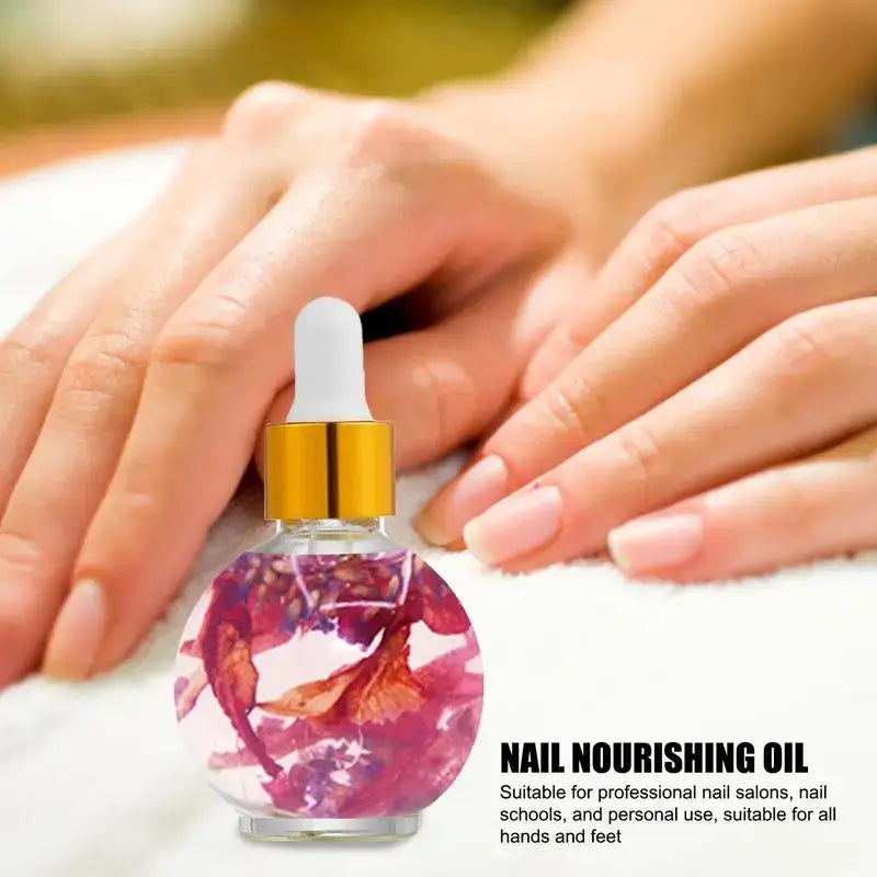 Glass bottle of nail nourishing oil containing pink flower petals.