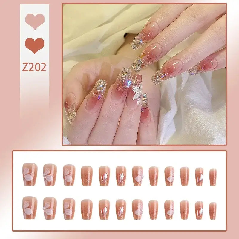 Elaborately decorated acrylic nails with glitter, floral designs, and a pink-to-clear gradient.