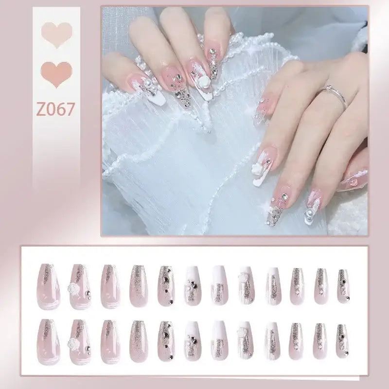 Elaborately decorated fingernails with glittery and floral designs in pale pink and white.