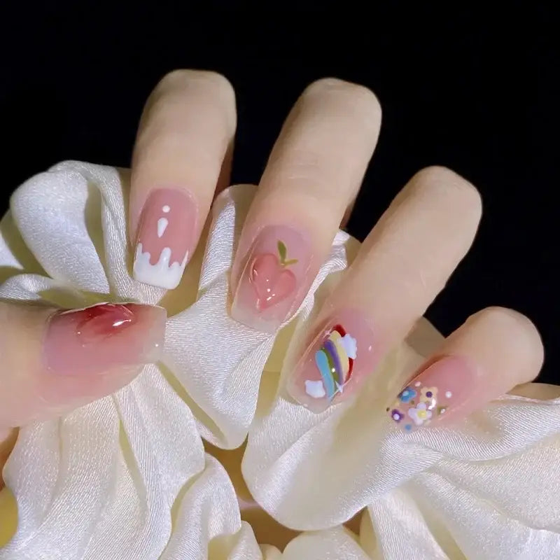 Hand with elaborately decorated fingernails featuring pink tones, floral designs, and abstract patterns.