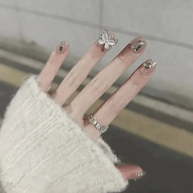 Hand with decorated nails and a butterfly-shaped ring.