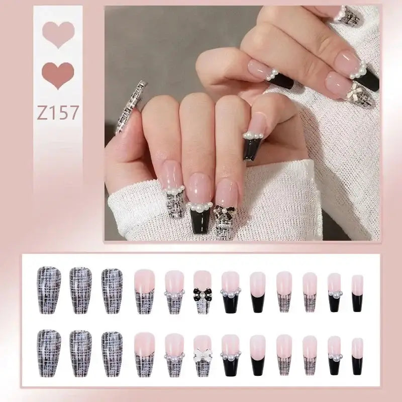 Manicured nails with French tips and decorative silver charms.