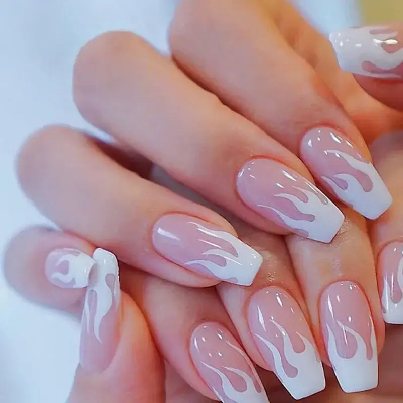 Manicured nails with a flame-like design in white on a pale pink base.