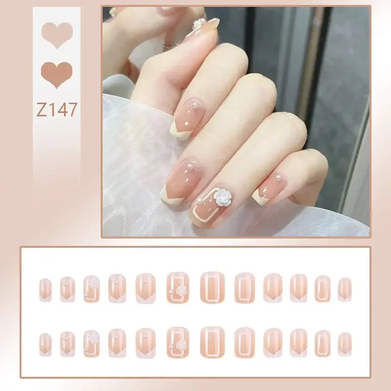 Manicured nails with a delicate pink and white design, featuring a small pearl accent on one nail.