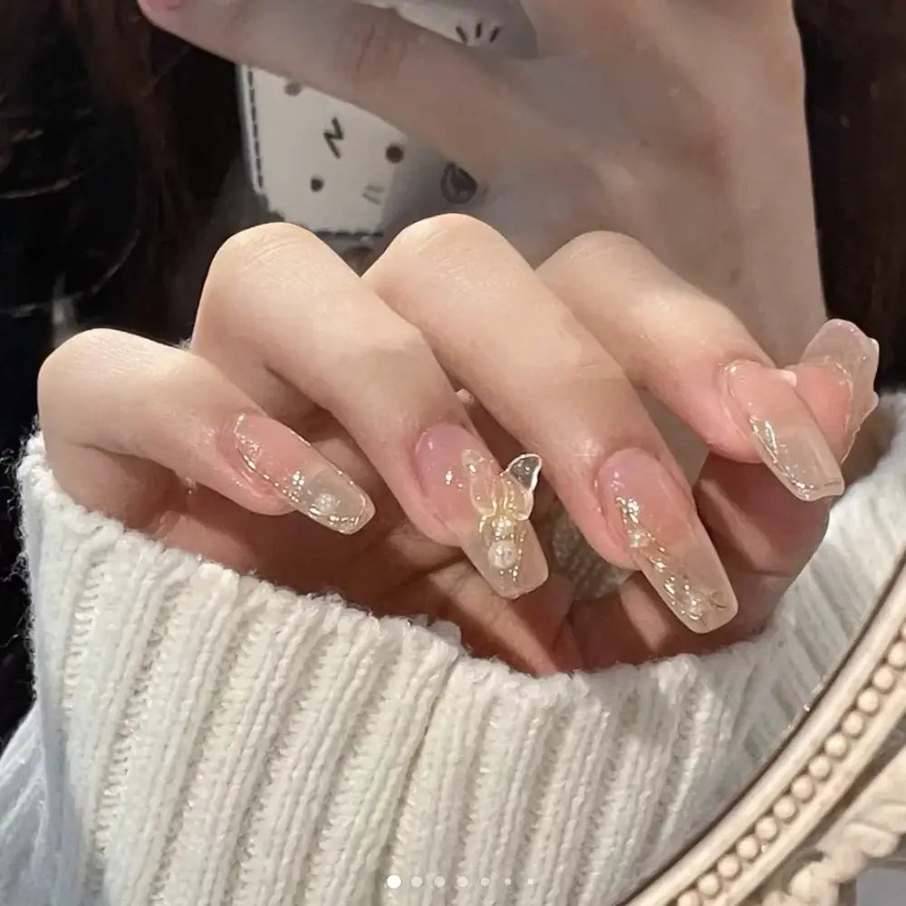 Manicured nails with glittery, translucent nail polish and gold accents.