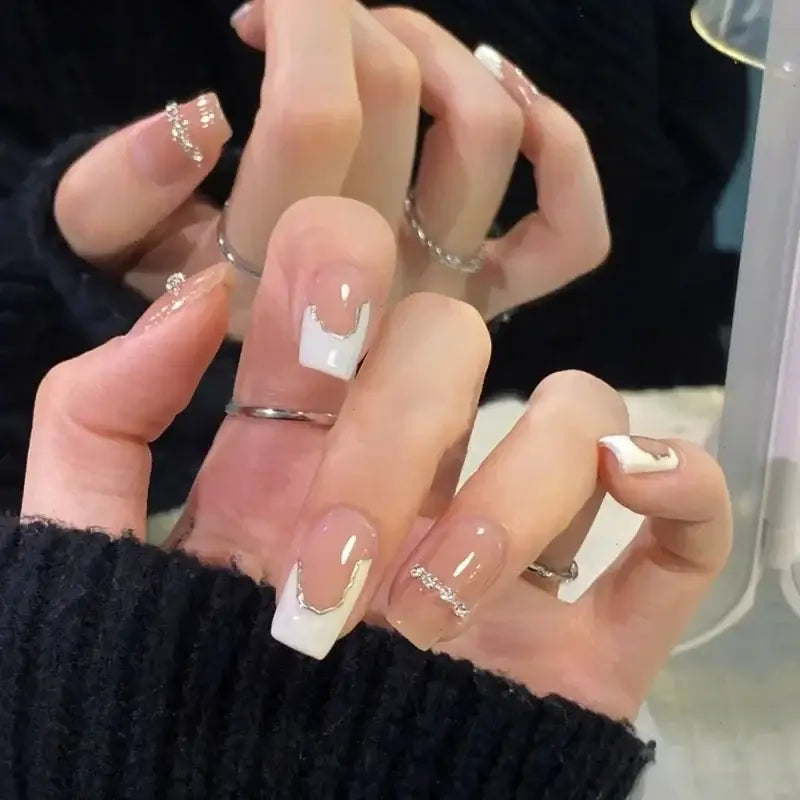 Manicured nails with French tips and delicate jewelry.