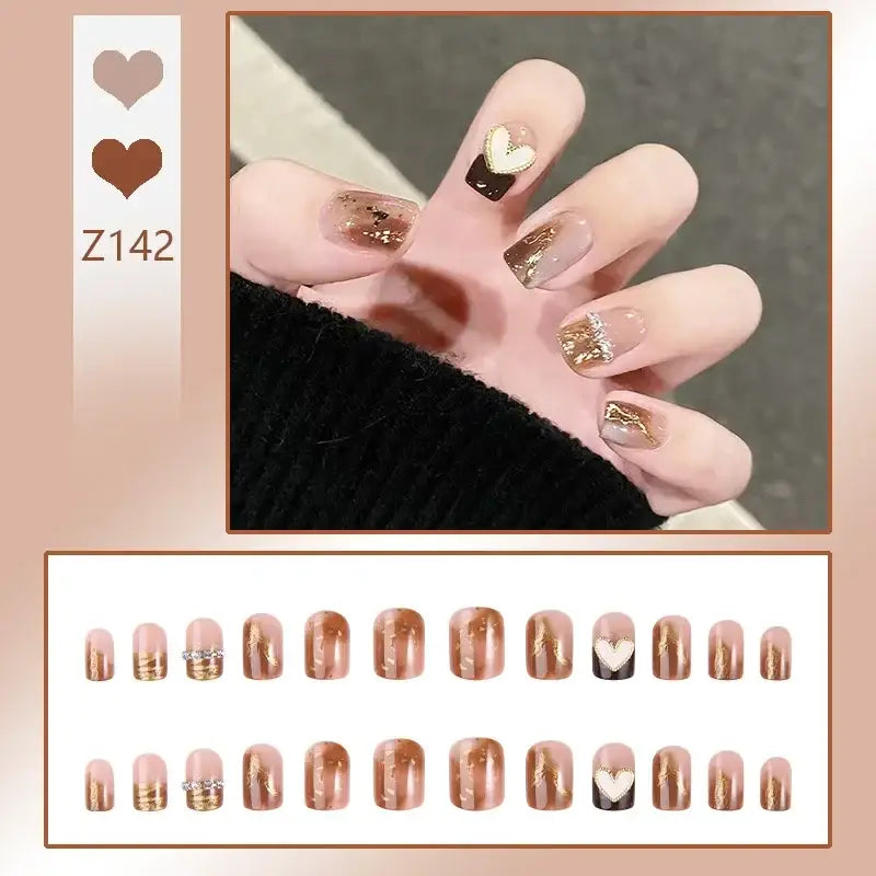 Manicured nails with gold and black designs on a pale pink base.