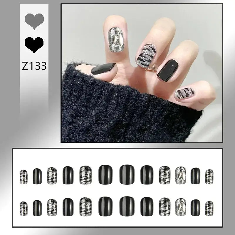 Manicured hand with black and silver patterned nail art.