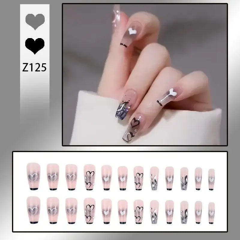 Manicured hand with decorative nail art featuring faces and designs on long, pointed nails.