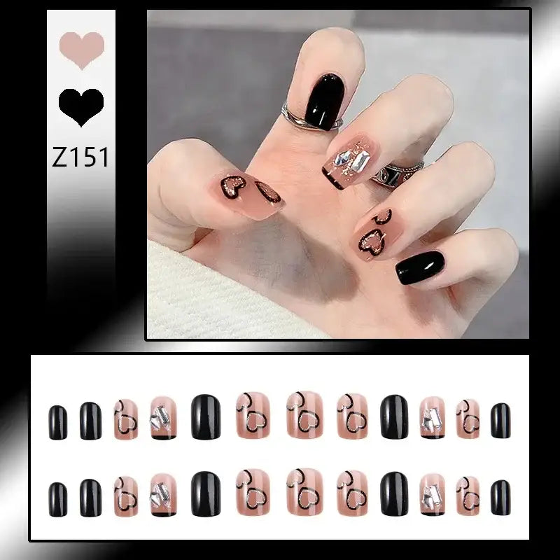 Manicured hand with black and nude nail art featuring heart designs.