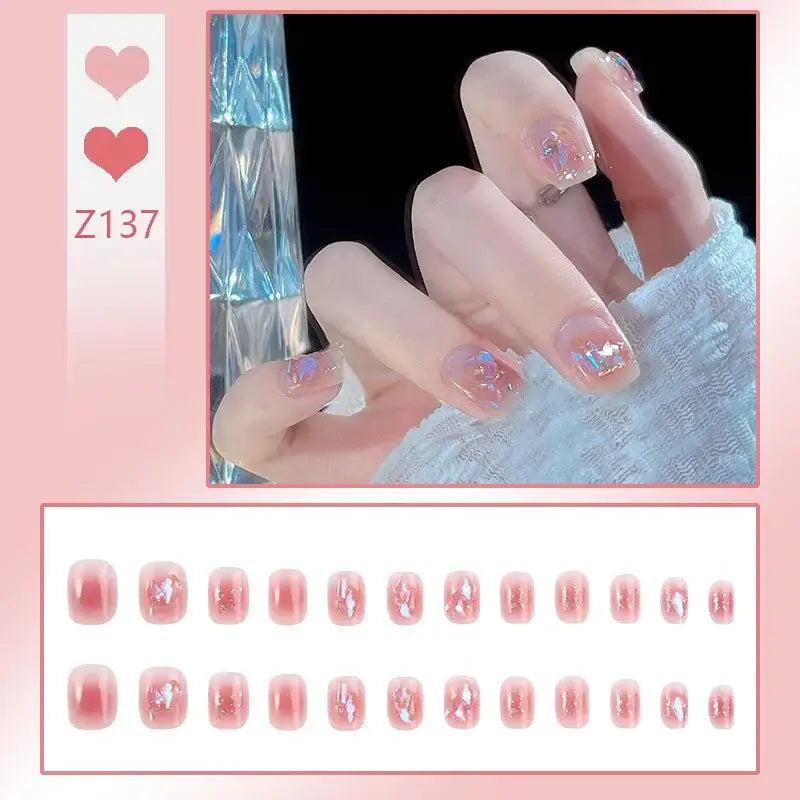 Manicured hand with glittery pink nail art and decorative elements.