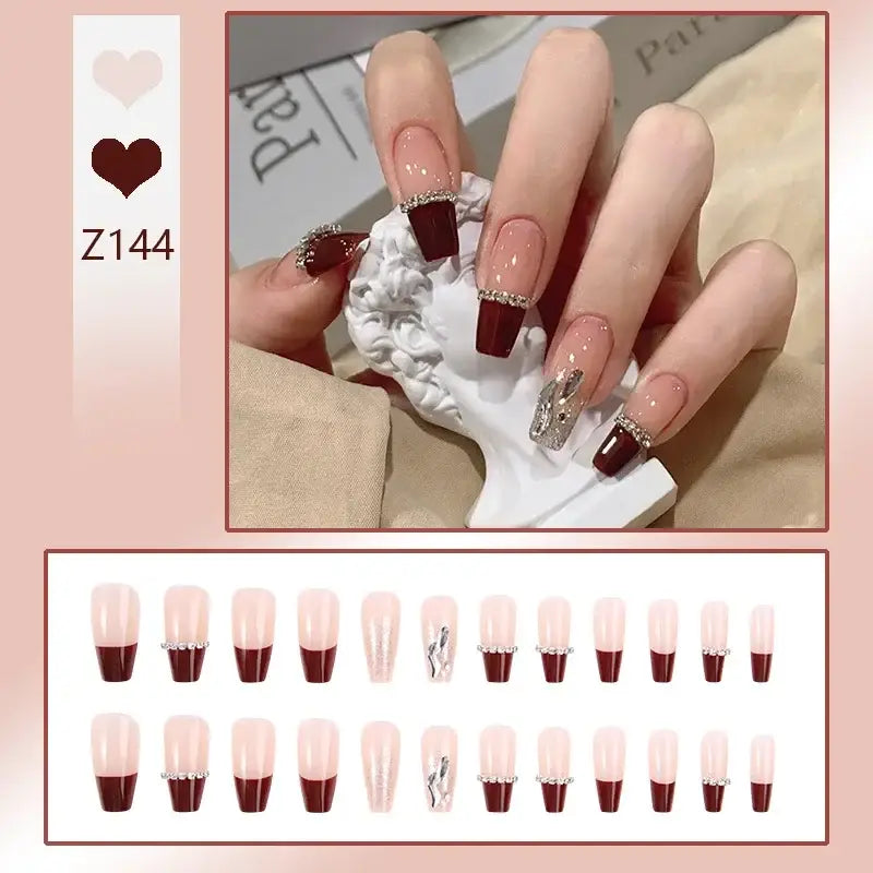 Manicured hand displaying French tip nails with burgundy tips and accent designs.