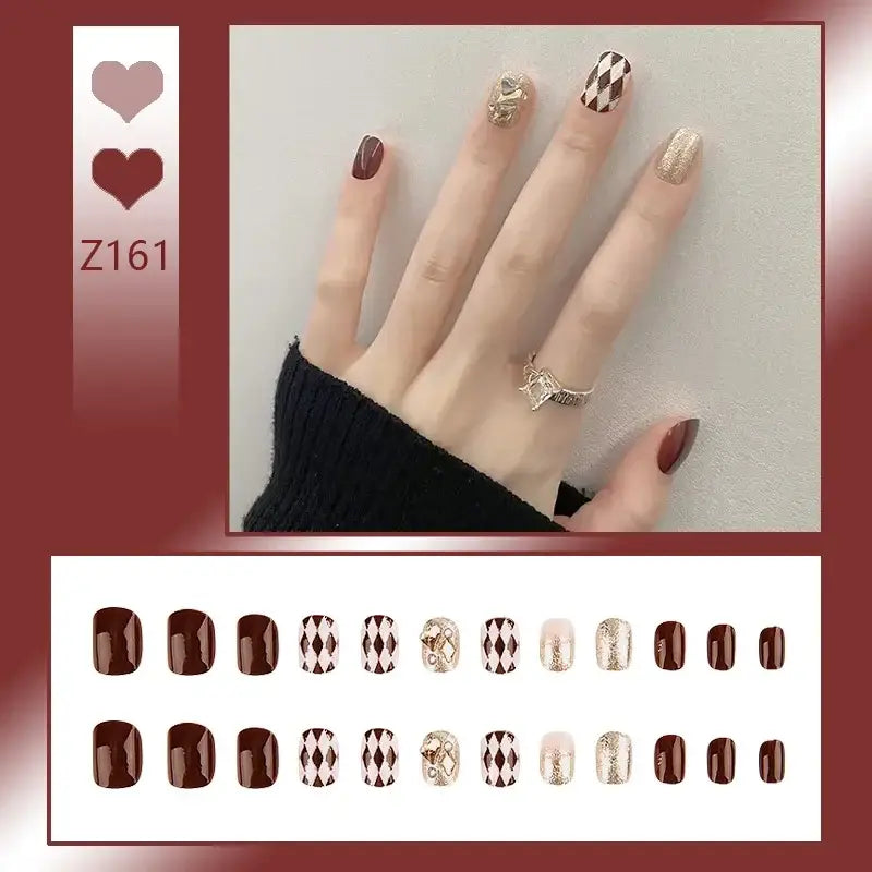 Manicured hand with burgundy and patterned nail art designs.