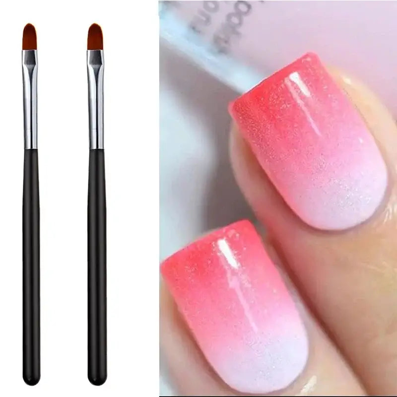 Ombre pink-to-white manicured fingernails alongside two nail art brushes.