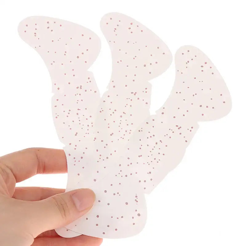 Pale pink, speckled, ghost-shaped sponge or bath accessory held between fingers.