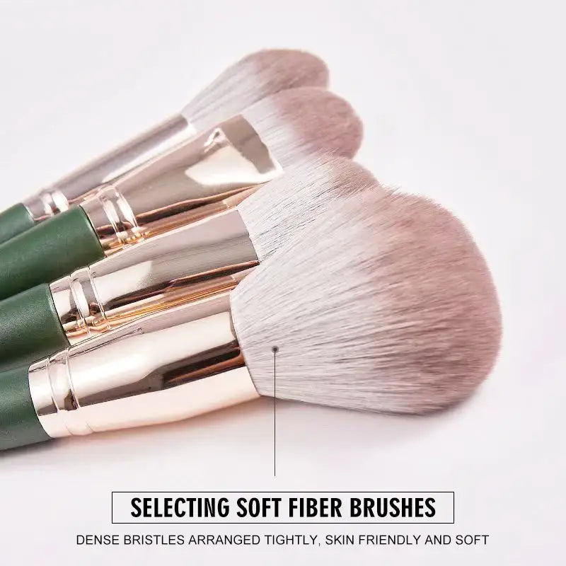 Set of makeup brushes with soft, white bristles and green handles.