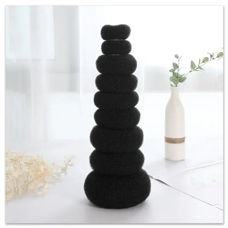 Stack of black circular cushions or discs arranged in a tower-like formation.