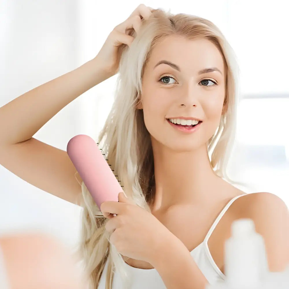 Smiling blonde woman holding a pink hairbrush.