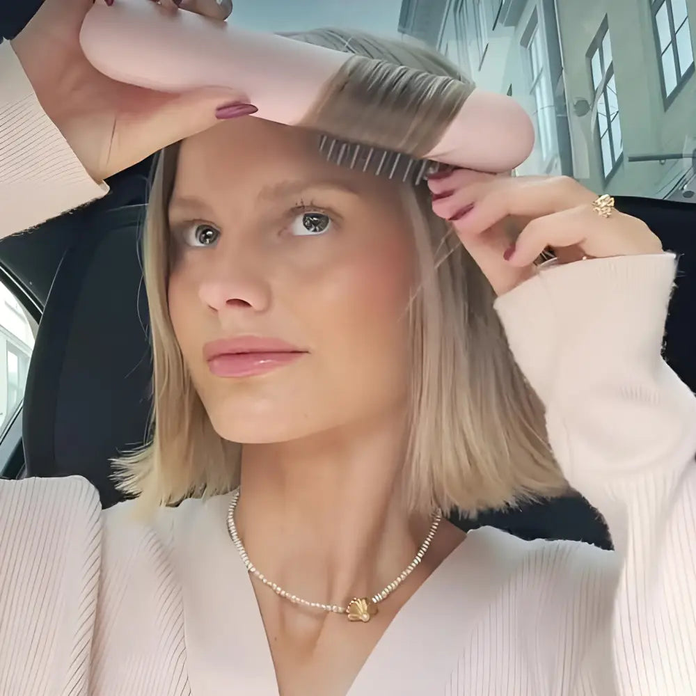 Woman brushing her blonde hair with a pink hairbrush.