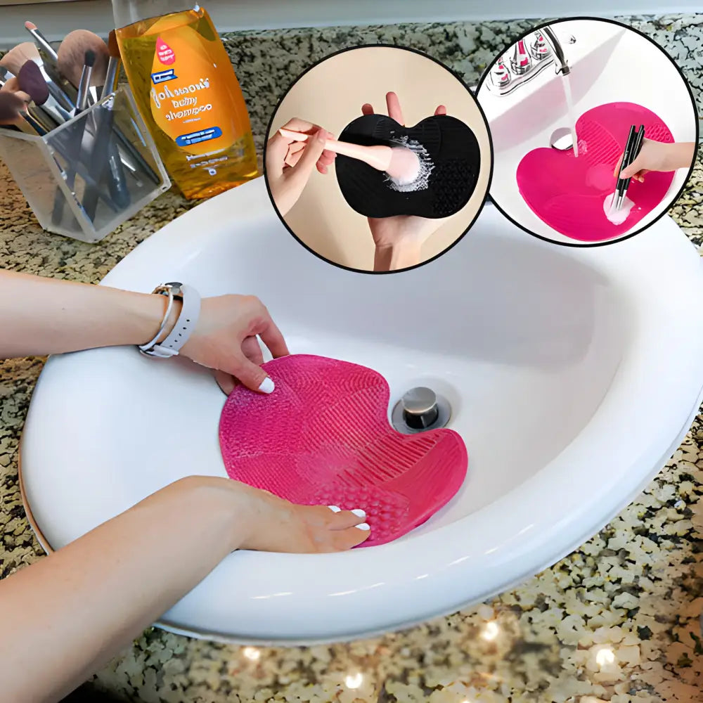 Pink silicone makeup brush cleaning mat in a sink.