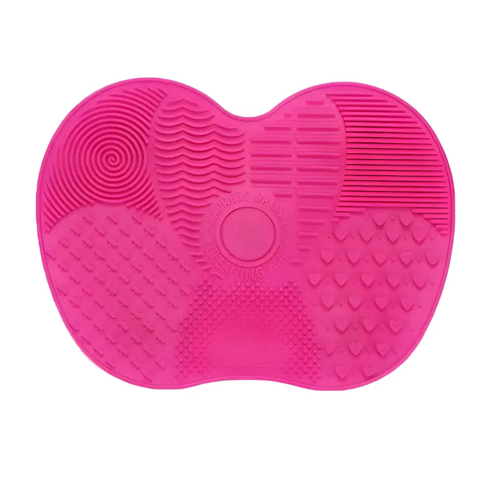 Heart-shaped pink silicone makeup brush cleaning mat with various textured sections.