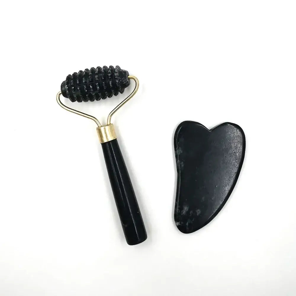 Facial massage roller with a black bristled head and a heart-shaped gua sha tool.