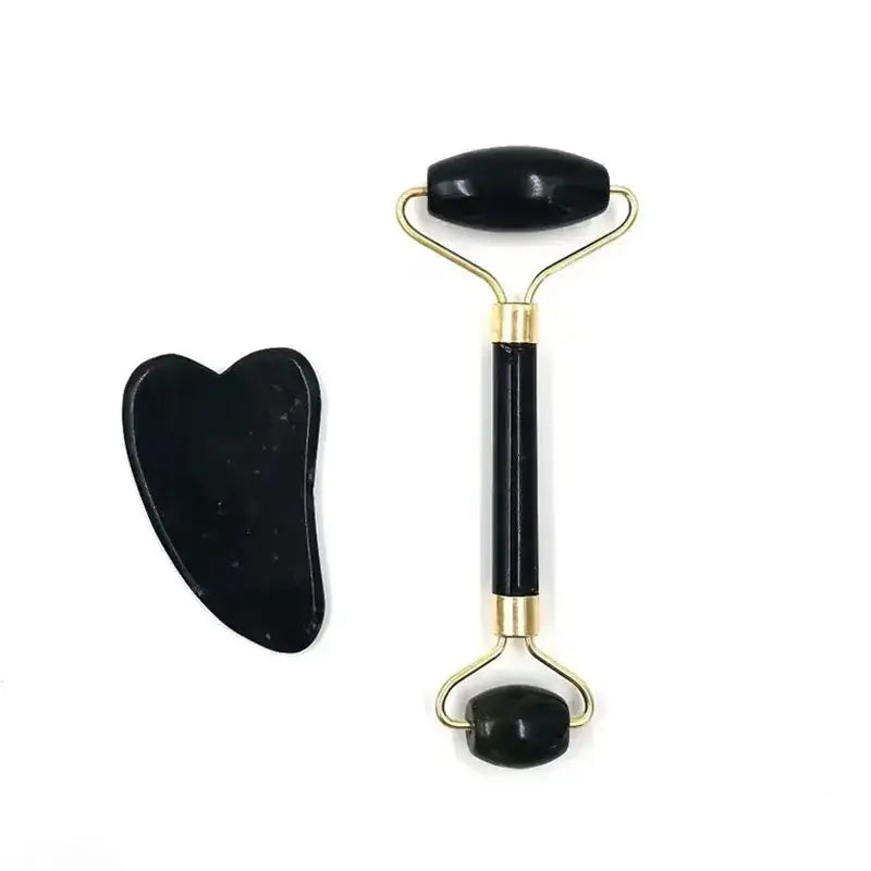 Facial massage roller with a black gua sha stone tool beside it.