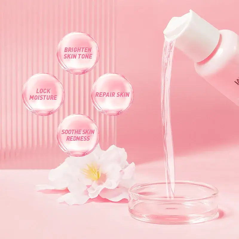 Pouring stream of pink skincare product or cosmetic cream into a container, with floating bubbles displaying skin benefits and a white flower nearby.