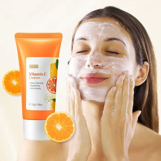 Vitamin C facial cleanser tube alongside orange slices and a person applying face cream.