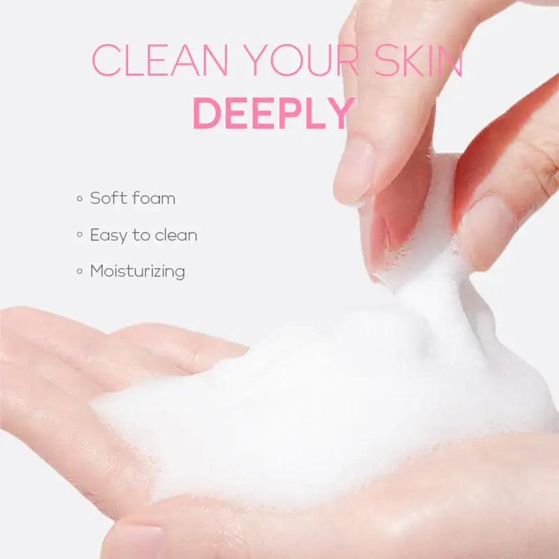 Soft, white foam being held between two hands with manicured nails.