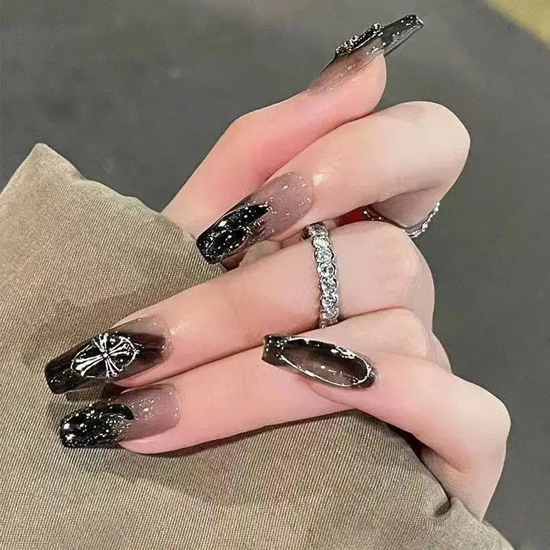 Hand with long, black and glittery acrylic nails and a diamond ring.