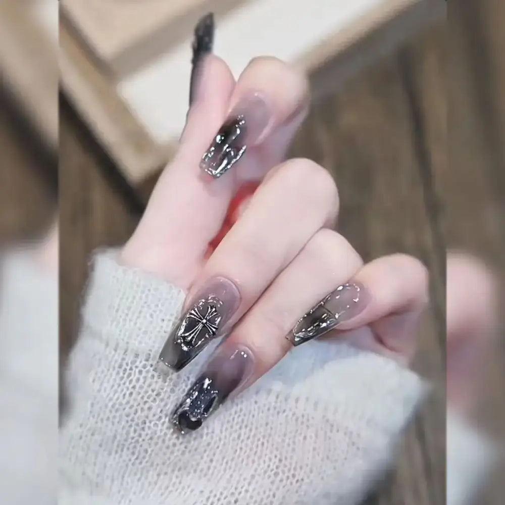 Hand with long, elaborately decorated acrylic nails in a dark, glittery design.