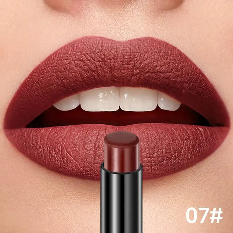 Close-up of lips wearing deep burgundy lipstick, with a matching lipstick tube below.