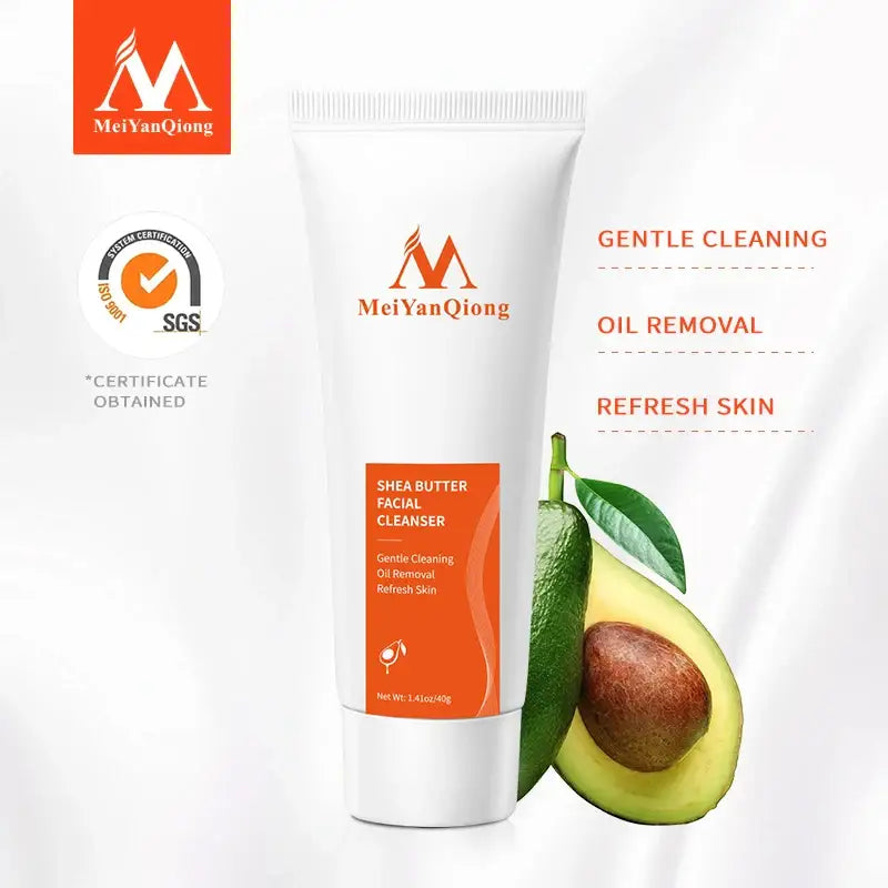 White tube of MeiYanQiong shea butter facial cleanser with orange packaging details, shown next to a halved avocado.