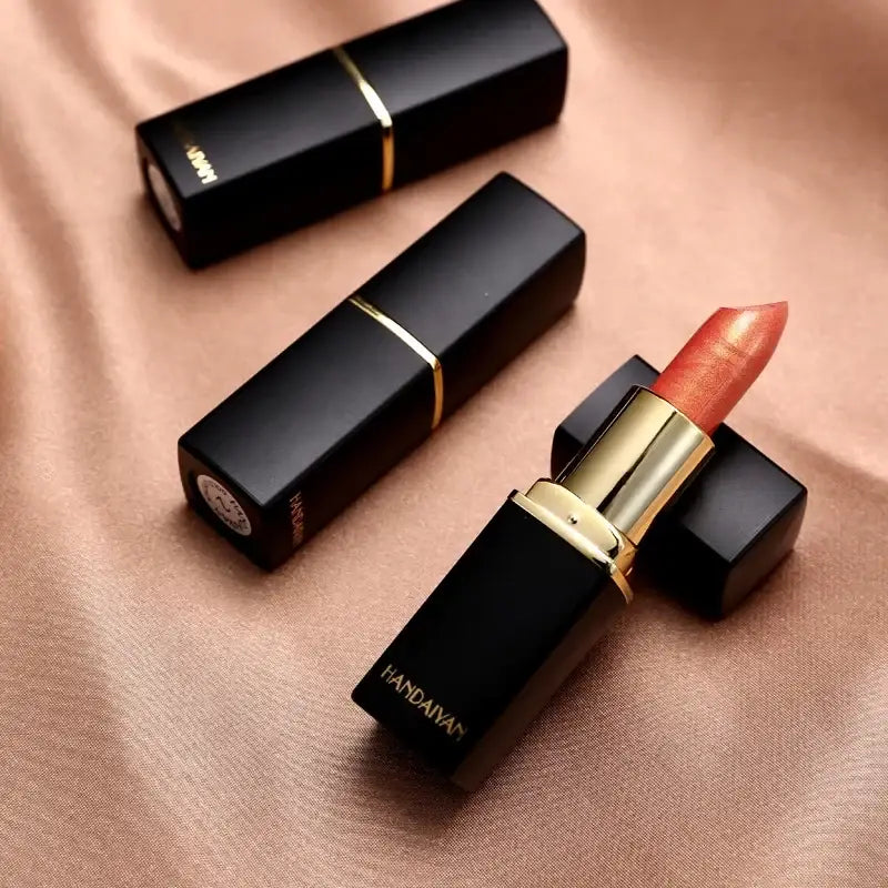 Luxurious black and gold lipstick with a coral-colored tip.