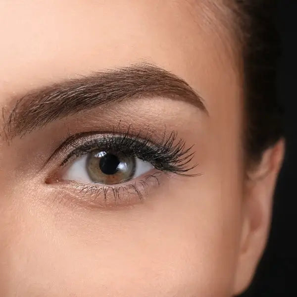 Close-up view of a human eye with long eyelashes and a well-groomed eyebrow.