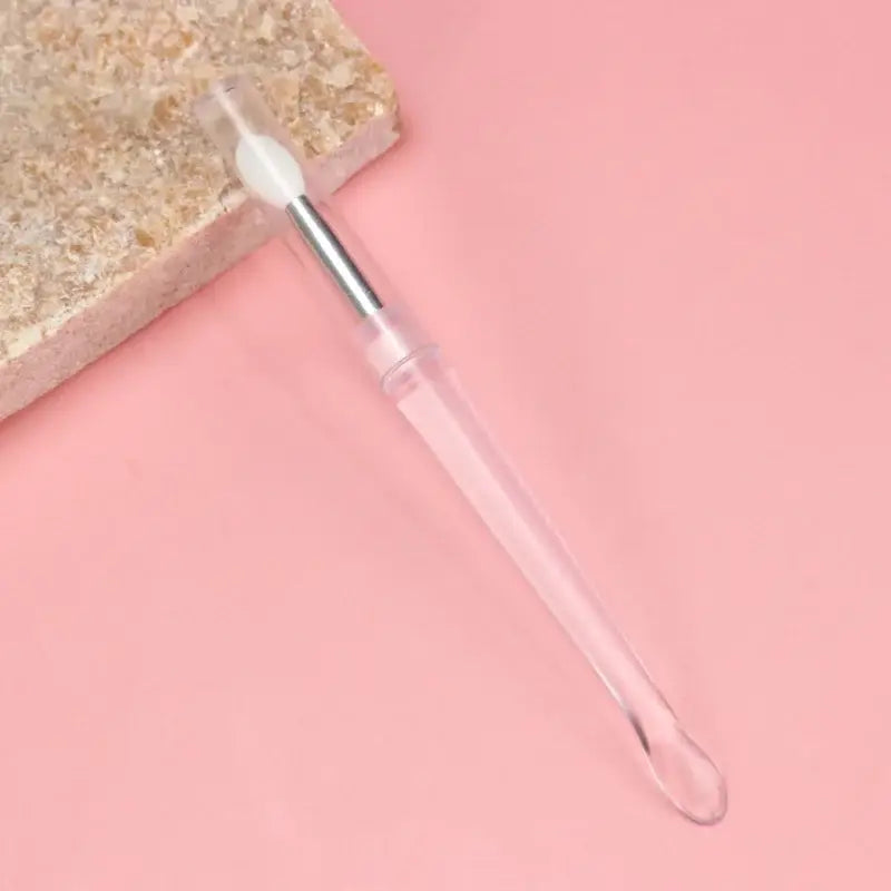 Nail file or cuticle pusher tool with a metal tip and clear plastic handle.